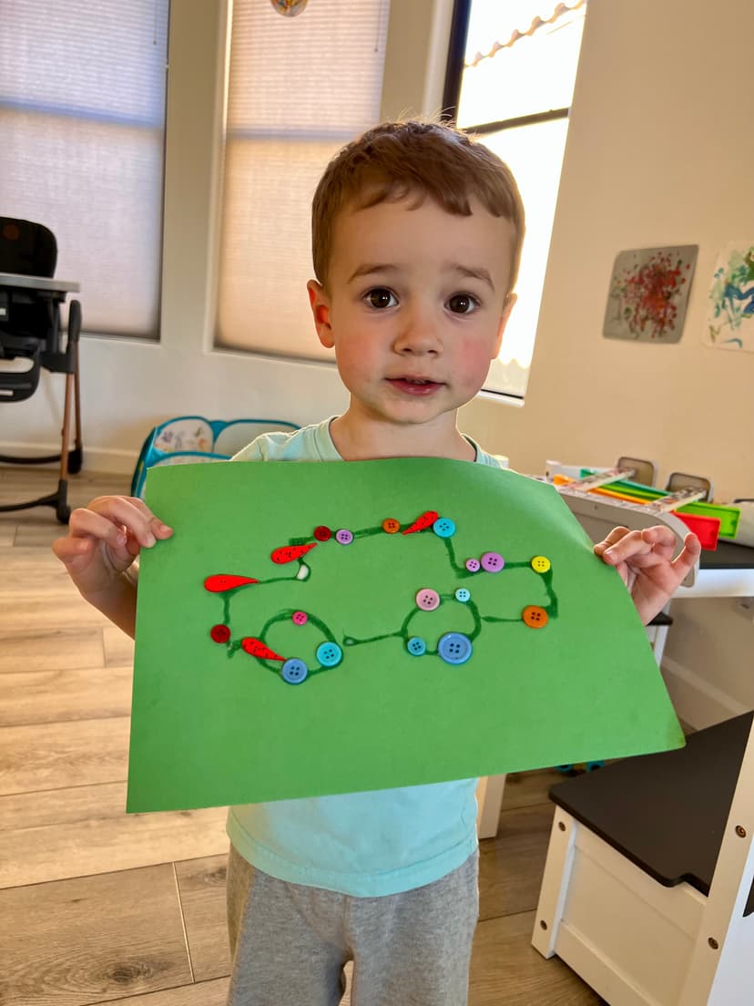 Little one proudly holding button art craft